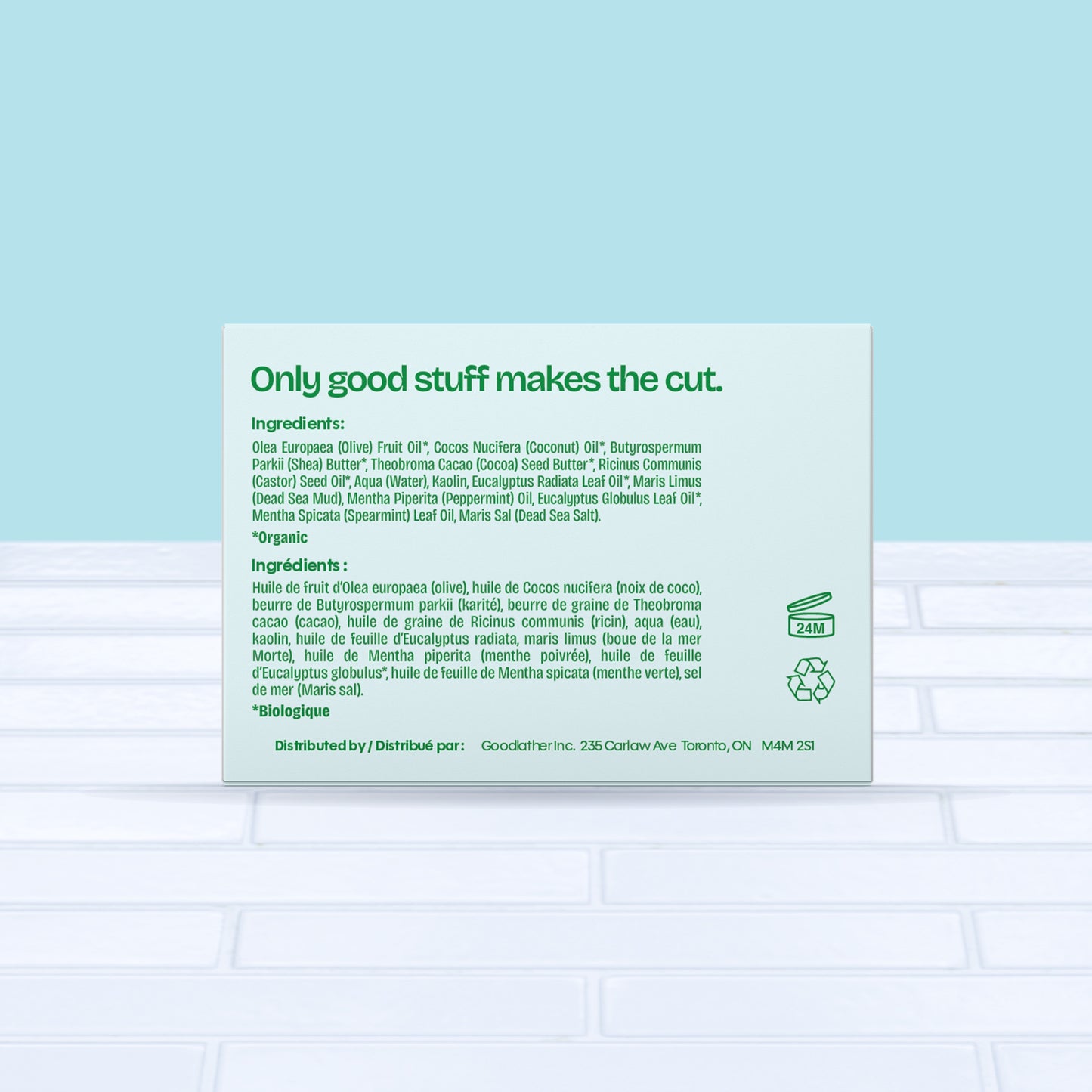 A square green and bright blue Goodlather Cedar Oakmoss Bar Soap box sits on white tile with a blue backdrop. Text reads "Only good stuff makes the cut," plus all natural ingredients and distribution details for this sustainable soap.