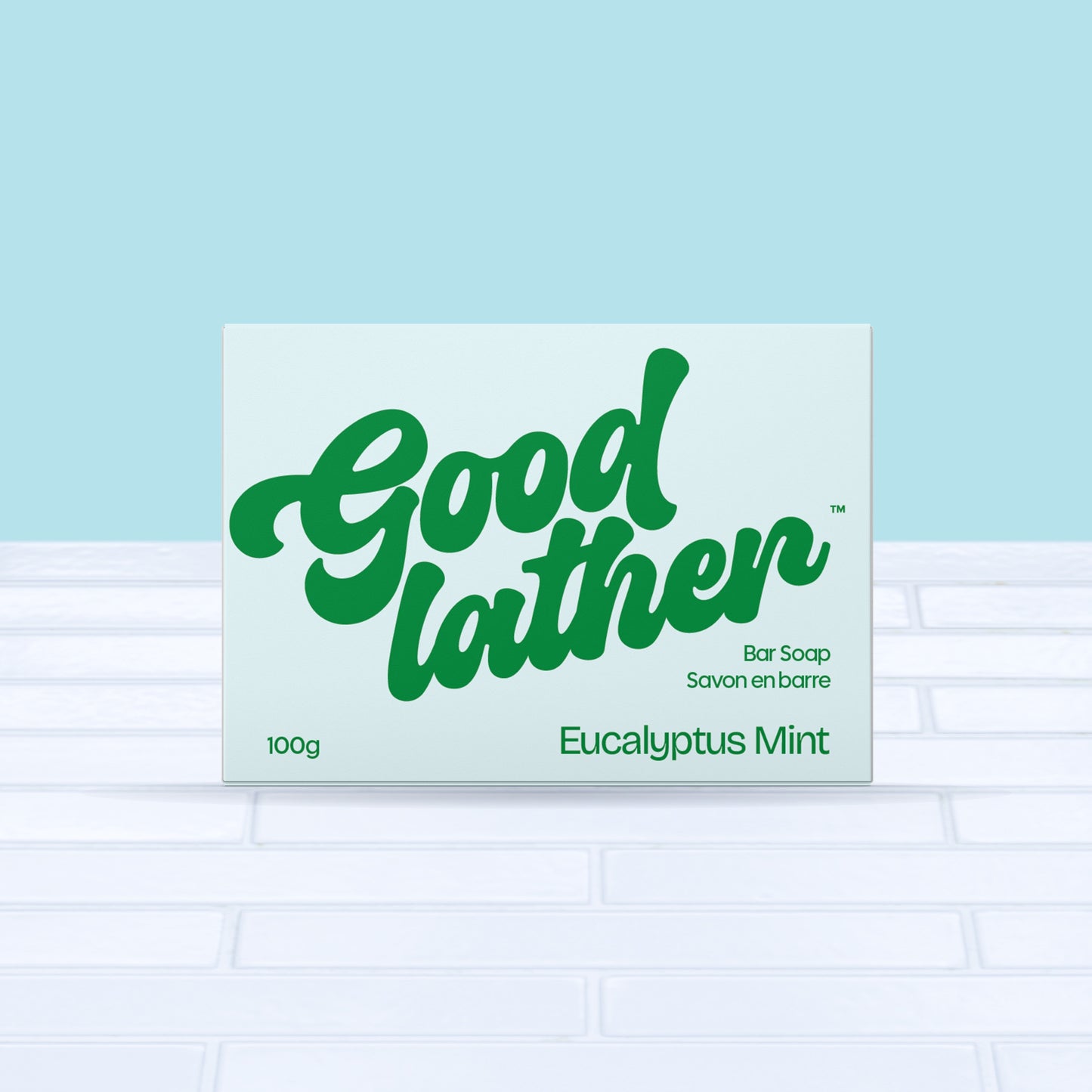 A box of Goodlather Eucalyptus Mint Bar Soap, with bold green text on a light blue background, rests on white tile against a light blue wall. Made with natural ingredients for a refreshing clean.