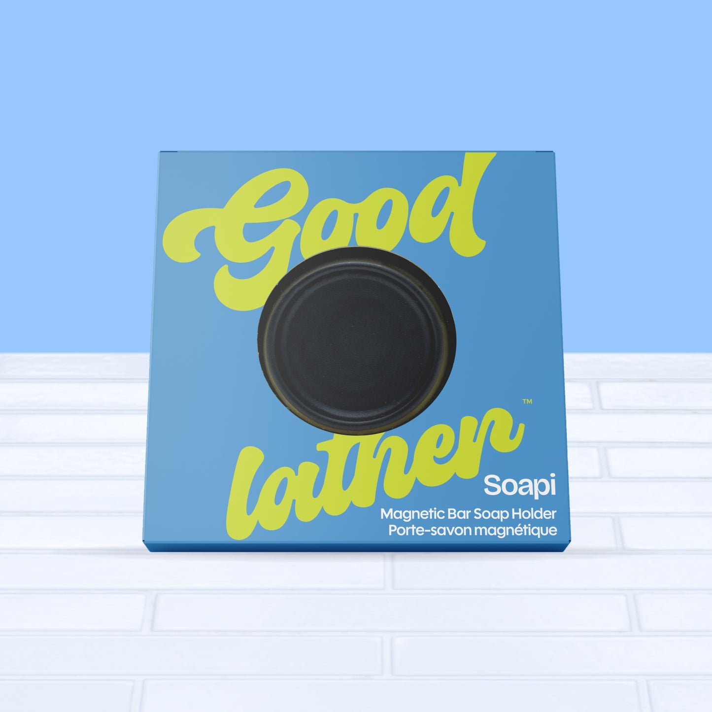 A black Goodlather Soapi Magnet Holder, a sustainable Canadian product, is shown on white tiles with a light blue background
